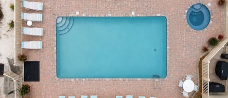 A rooftop swimming pool with lounge chairs and tables arranged around it.