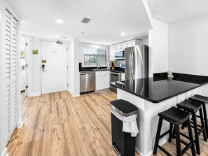 Une cuisine moderne dotée d’un îlot central, d’appareils électroménagers en acier inoxydable et d’un revêtement de sol en bois.