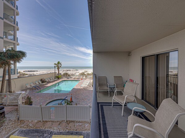 Área da piscina com espreguiçadeiras, uma piscina pequena e vista para a praia.
