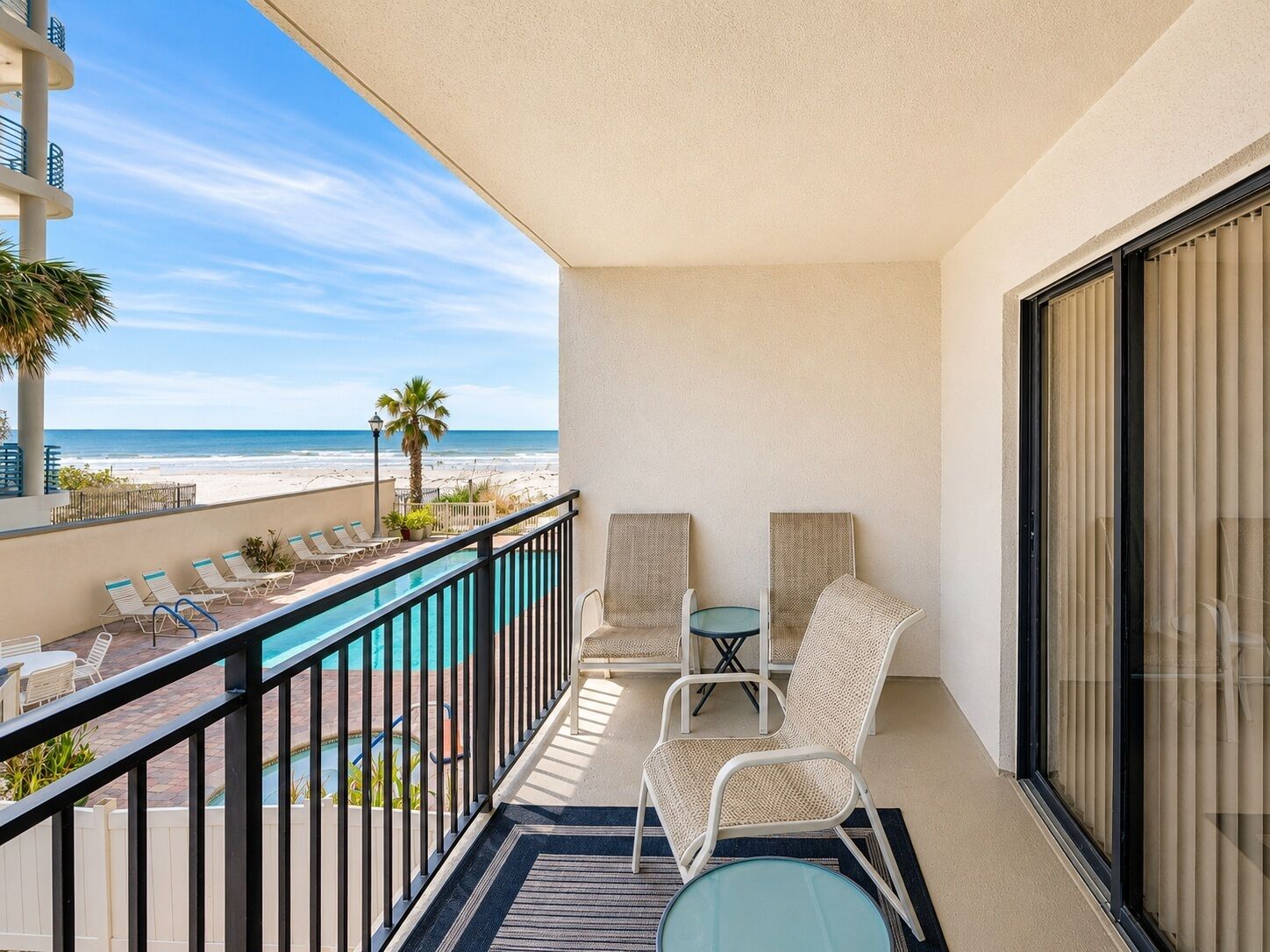 Un balcon avec une piscine, des chaises longues et une vue sur la plage.