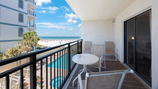 Een balkon met een zwembad, stoelen en uitzicht op het strand en de oceaan.