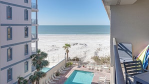Een balkon van een hotel met uitzicht op een strand en een zwembad.