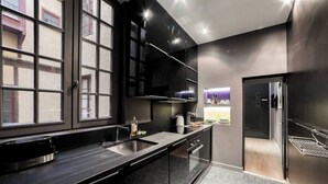 A modern kitchen with a large window, dark cabinetry, and stainless steel appliances. - La Cachette St Jean: Calm and serenity in Vieux Lyon (Lyon)