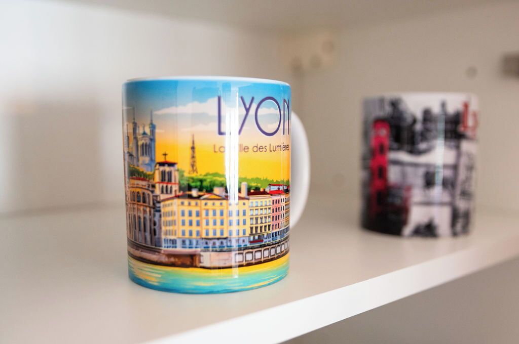 A mug with a cityscape design, placed on a shelf.