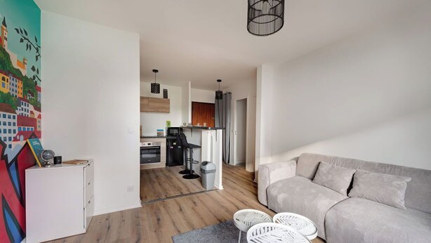 A modern living room with a grey sofa, white chairs, and a kitchen in the background. - Au Lyon D'ort - Near Eurexpo (Villeurbanne)