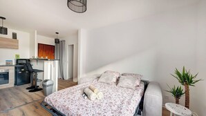 A modern bedroom with a bed, bedside tables, a small desk, and a potted plant. - Au Lyon D'ort - Near Eurexpo (Villeurbanne)