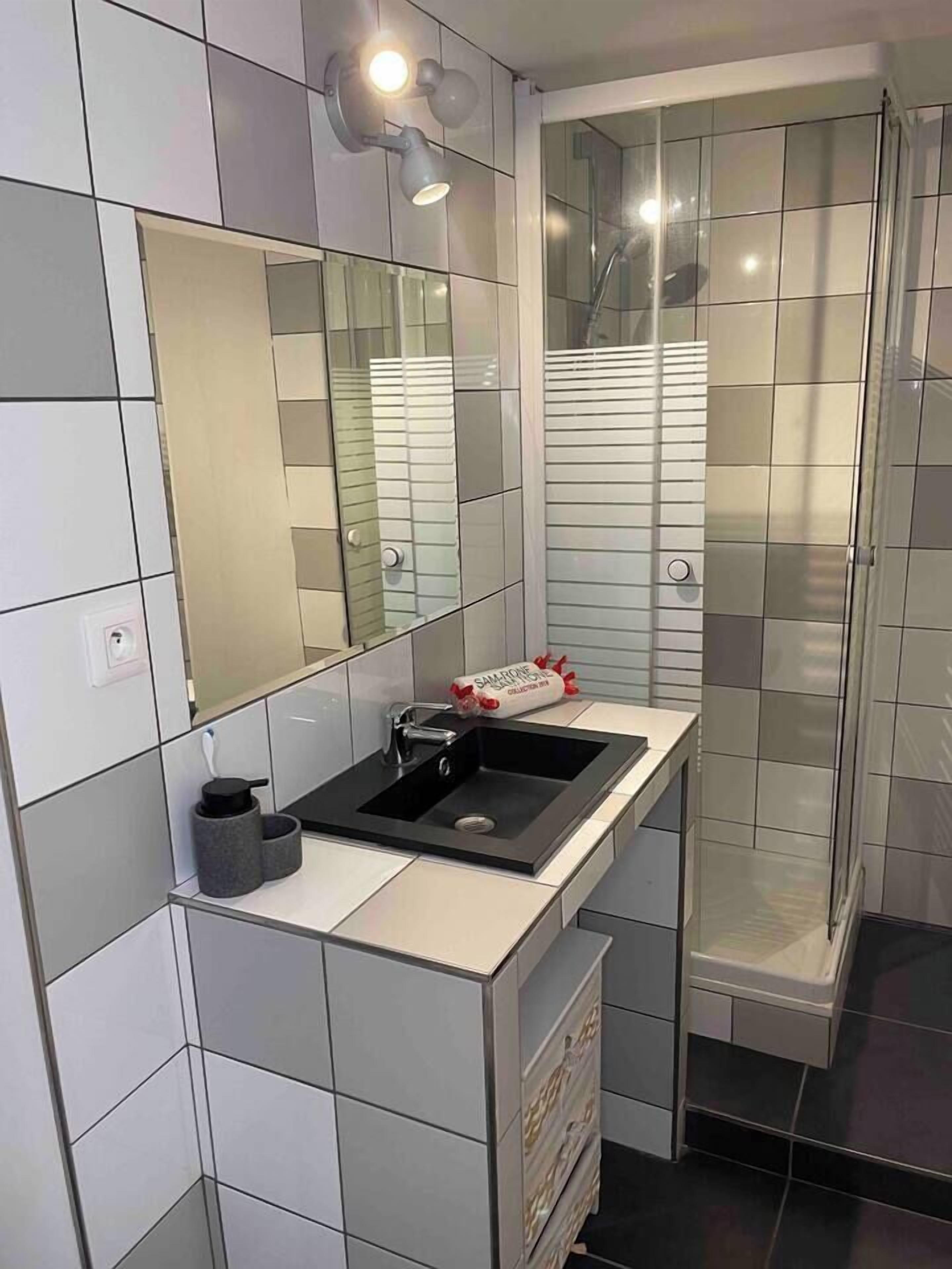 Een moderne badkamer met een wit wastafelmeubel, een spiegel en een douchecabine.