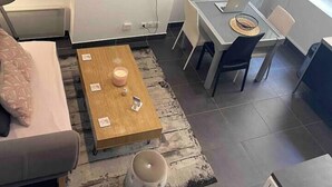 A modern living room with a sofa, a coffee table, a TV mounted on the wall, and a dining area with a table and chairs. - Le Masséna d'Or: Quiet, Metro + Parc Tête D'or (Lyon)