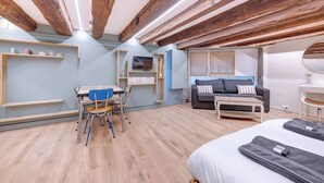 Une chambre moderne avec des poutres apparentes, un bureau avec des chaises, un canapé et un lit.