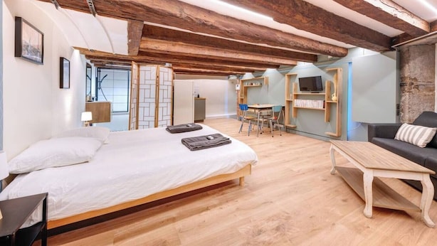 Une pièce spacieuse comprenant un grand lit, une table basse en bois, un canapé et un coin repas avec une table et des chaises.