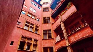 A narrow alleyway between buildings with a large arched entrance and barred windows.
