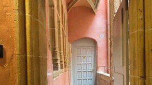 A narrow corridor with a wooden floor, a white door at the end, and walls painted in a warm tone.