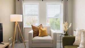 Un salon moderne avec un canapé, une lampe sur pied et un téléviseur.