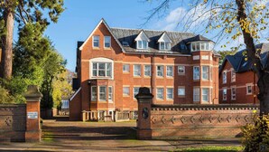 A large, red brick building with multiple windows and a prominent corner turret. - Modern | 2 Bed | Chestnut Court Leamington Spa (Royal Leamington Spa)