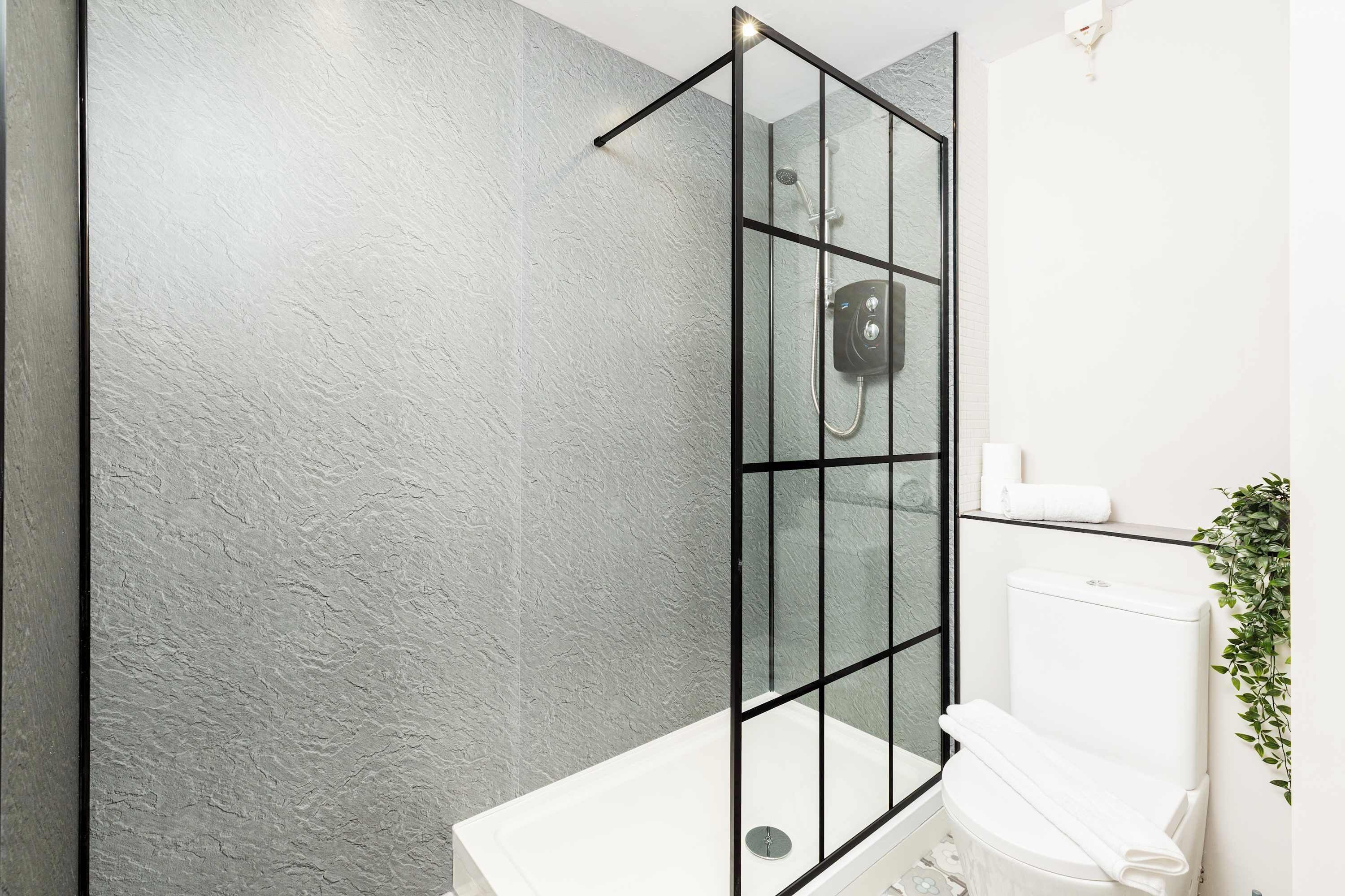 Une salle de bain moderne avec une douche à parois de verre, une baignoire blanche et des toilettes.
