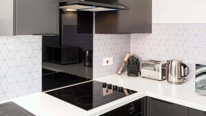 Una cocina moderna con estufa negra, horno integrado, tostadora y hervidor.