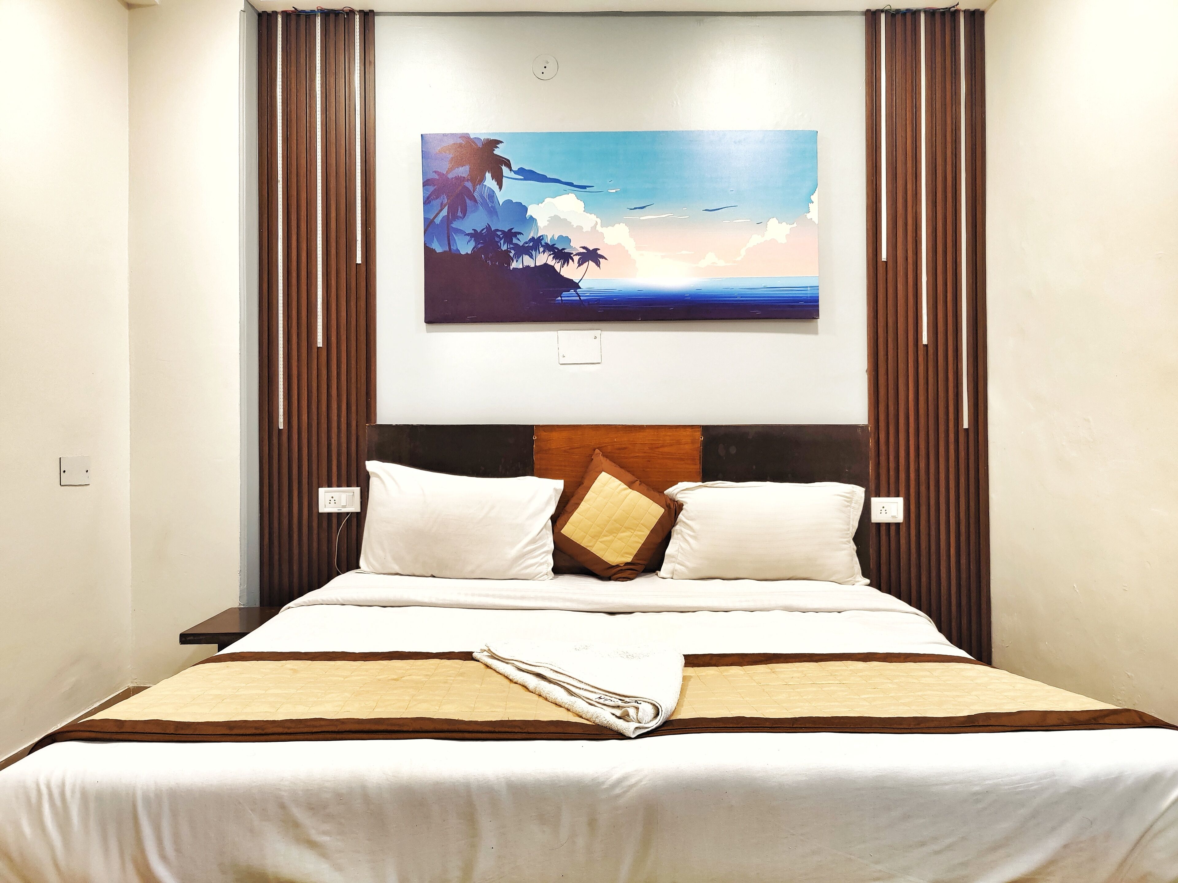 A neatly made bed with a white and brown bedspread, two pillows, and a folded towel.