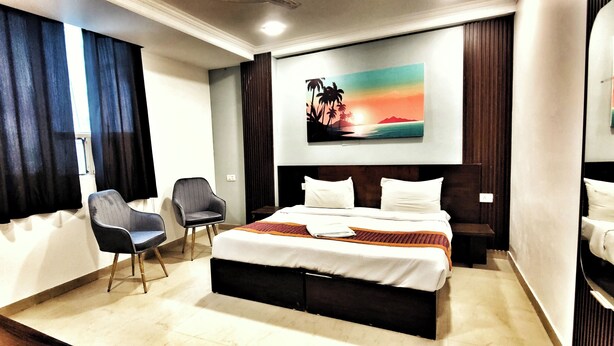 A hotel room with a bed, a chair, a painting, and a large mirror. - Hotel the terminal (New Delhi)