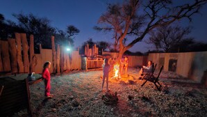 An outdoor area with a fire pit, a wooden fence, and a gravel ground. - Buffelkraal Safaris (Mogalakwena)