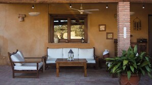 Un espacio de estar al aire libre cubierto con una mesa de madera, dos sillas, un sofá y una planta en maceta.