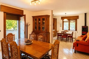 A dining area with a wooden table and chairs, a cabinet, and a red sofa.