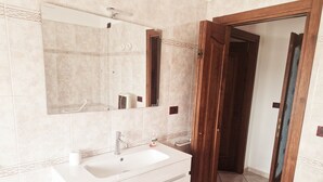 A bathroom with a white sink, a mirror, and a wooden door. - Cà Elena house located in the Po Delta park a few kilometers from Lido di Volano  (Emilia-Romagna)