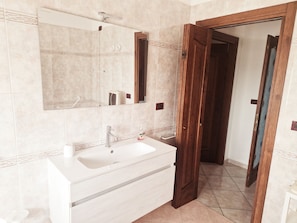 A bathroom with a white sink, a mirror, and a wooden door. - Cà Elena house located in the Po Delta park a few kilometers from Lido di Volano  (Emilia-Romagna)
