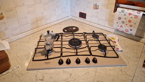 A kitchen with a gas stove, a coffee maker, and a tiled backsplash. - Cà Elena house located in the Po Delta park a few kilometers from Lido di Volano  (Emilia-Romagna)