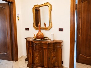 A wooden cabinet with a mirror above it, a vase, and a small white object on top. - Cà Elena House in the Po Delta Park, a few kilometers from Lido di Volano (Emilia-Romagna)