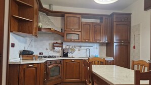 A kitchen with wooden cabinets, a gas stove, a built-in oven, and a marble countertop. - Cà Elena house located in the Po Delta park a few kilometers from Lido di Volano  (Emilia-Romagna)
