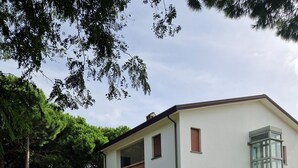 A two-story building with a flat roof, a balcony on the upper floor, and a glass door on the right side. - Cà Elena house located in the Po Delta park a few kilometers from Lido di Volano  (Emilia-Romagna)