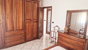 A bedroom with a large wardrobe, a dresser, a bed, and a mirror. - Cà Elena house located in the Po Delta park a few kilometers from Lido di Volano  (Emilia-Romagna)
