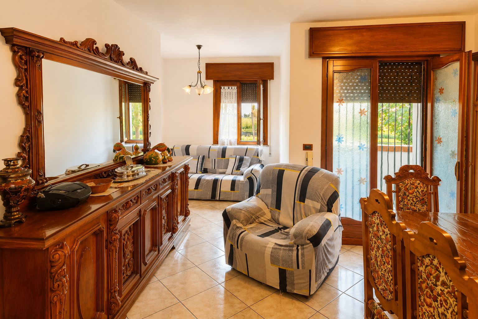 A traditional living room with a sofa, armchair, wooden sideboard, and a large mirror.
