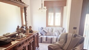 A living room with a sofa, a wooden cabinet, and a mirror. - Cà Elena house located in the Po Delta park a few kilometers from Lido di Volano  (Emilia-Romagna)