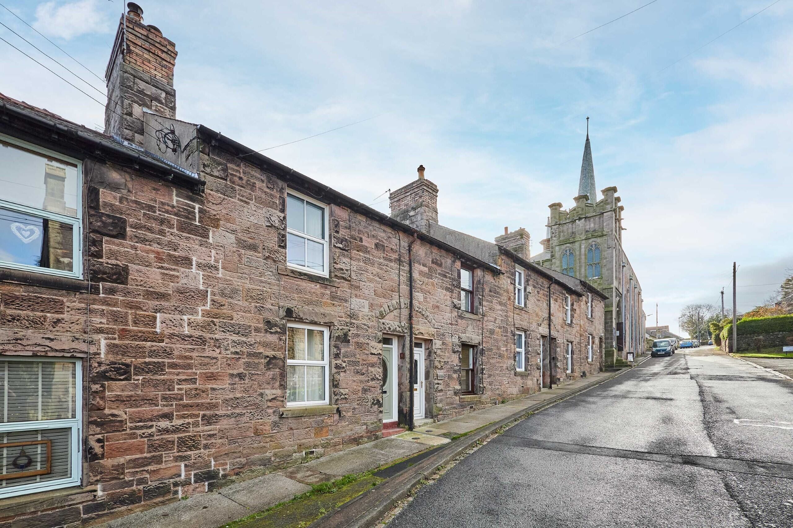 A row of traditional stone buildings with a church steeple in the background.