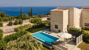 Una villa moderna con piscina, area relax esterna e vista sul mare.