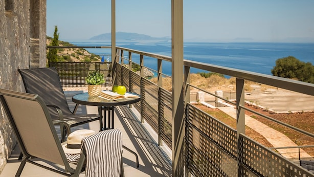 Ein Balkon mit Tisch, Stühlen und Meerblick.