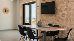 Ein Essbereich mit Steinwand, Flachbildfernseher und Meerblick.