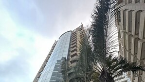 A high-rise building with a glass facade, palm trees, and a geometric metal structure. - Loft-In Jardins Ibirapuera X (Paraíso São Paulo)