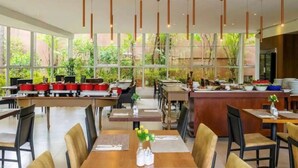 A spacious restaurant with high ceilings, modern pendant lighting, and large windows offering a view of greenery outside. - Loft-In Jardins Ibirapuera X (Paraíso São Paulo)
