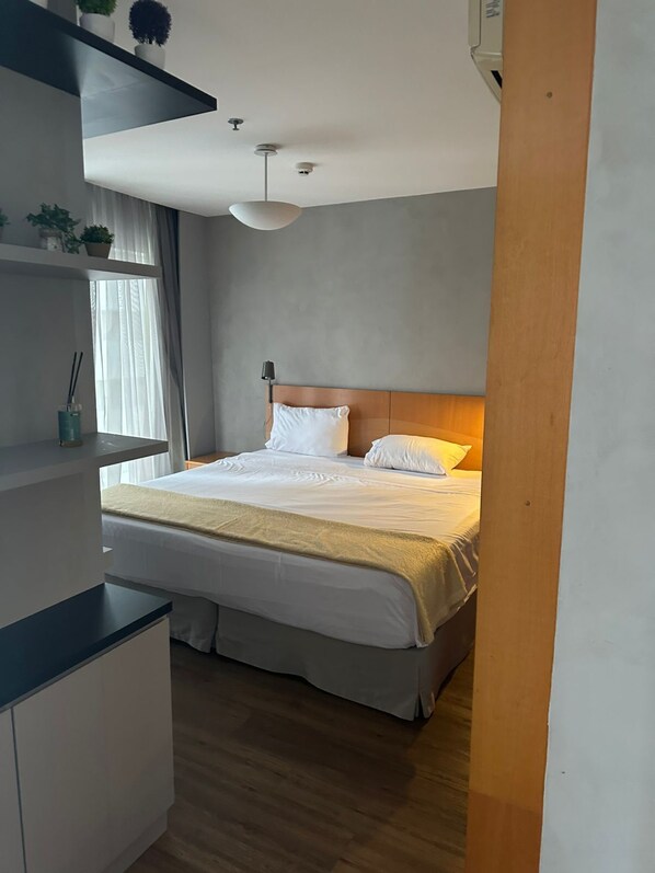 A modern bedroom with a bed, bedside tables, a window with curtains, and a ceiling fan.