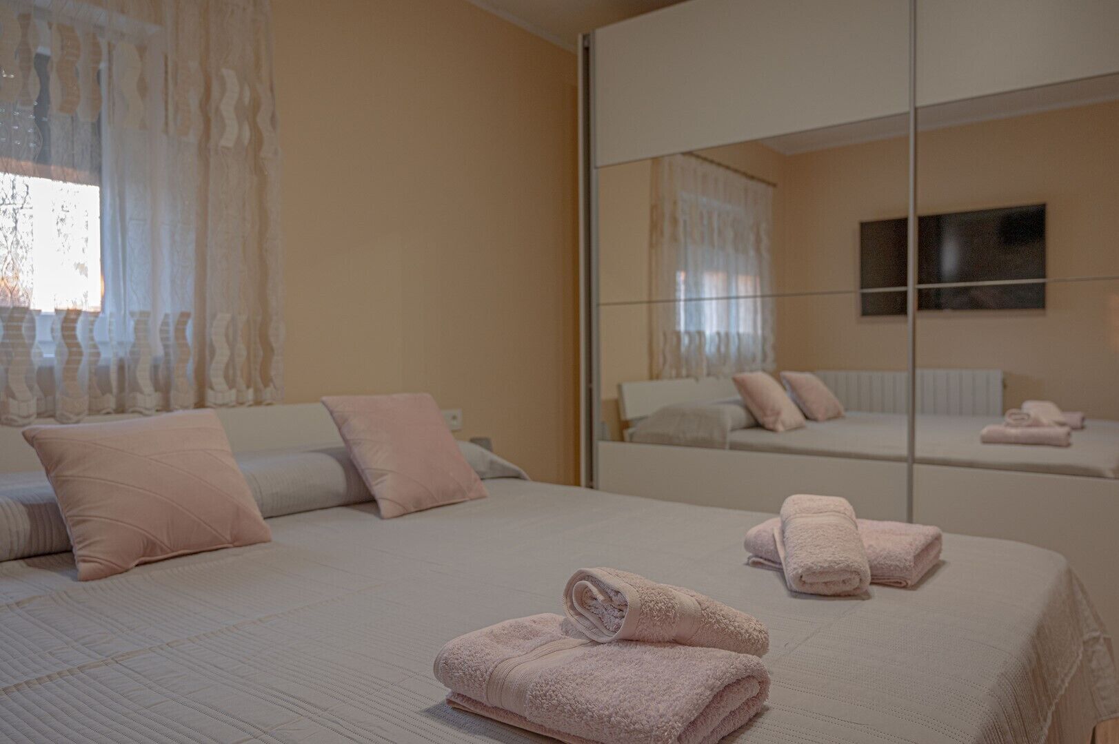 A bedroom with a large bed, a mirror, and a view of another room.