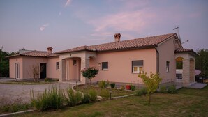 A two-story house with a tiled roof, a stone foundation, and a well-maintained garden. - Poolside Holiday House (Labin)