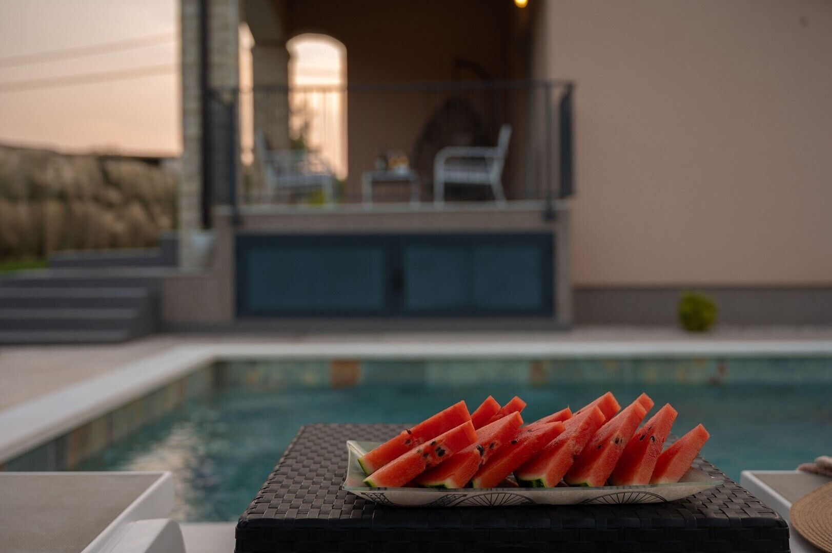 Ein Tisch am Pool mit Wassermelonenstücken.