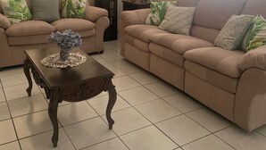 Ein Wohnzimmer mit zwei beigen Sofas, einem Holztisch und einer Stehlampe.