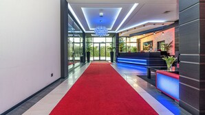 A modern hotel lobby with a red carpet, a reception desk, and a large chandelier. - Hotel Soray (Wieliczka)