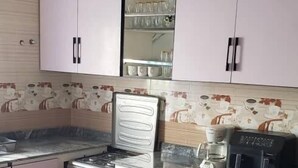 Une cuisine équipée d’une cuisinière, d’un four et de placards. On y trouve également une table à manger avec des chaises.