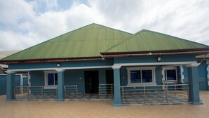Un bâtiment doté d’un toit végétalisé et de murs bleus, avec une entrée couverte et une rambarde en métal.