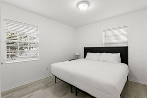 Quarto com uma cama grande, paredes brancas e uma luminária no teto.