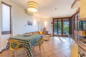 A dining area with a checkered tablecloth, chairs, and a view of the outdoors through a glass door. - Tina Home Lake View (Garda)